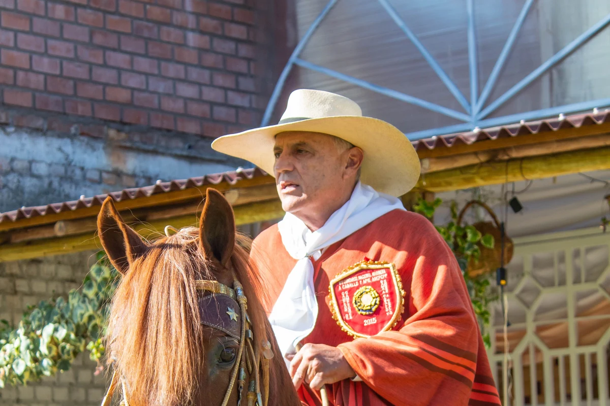 A mounted rider in a wide-brimmed straw hat and poncho, representative of a chalan's traditional dress